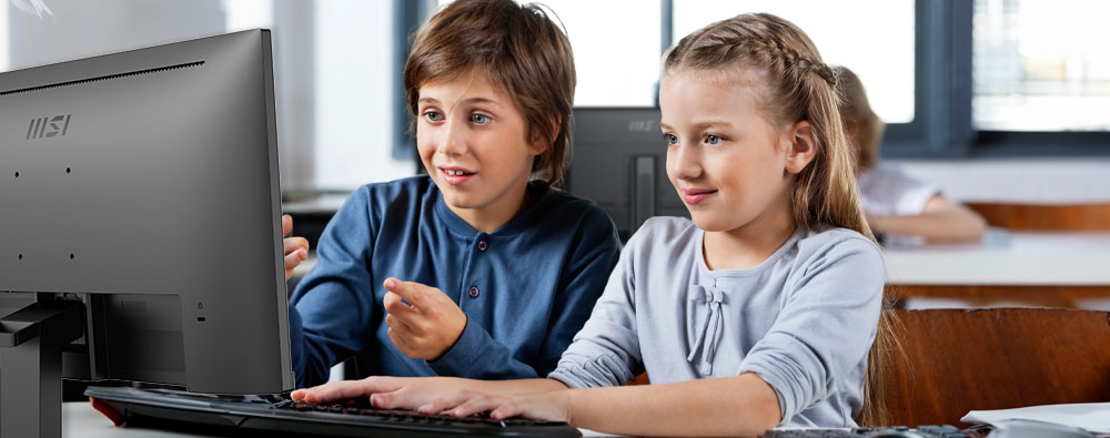 Two students studying a digital lesson on a desktop computer in a classroom, demonstrating a solution for the education sector.